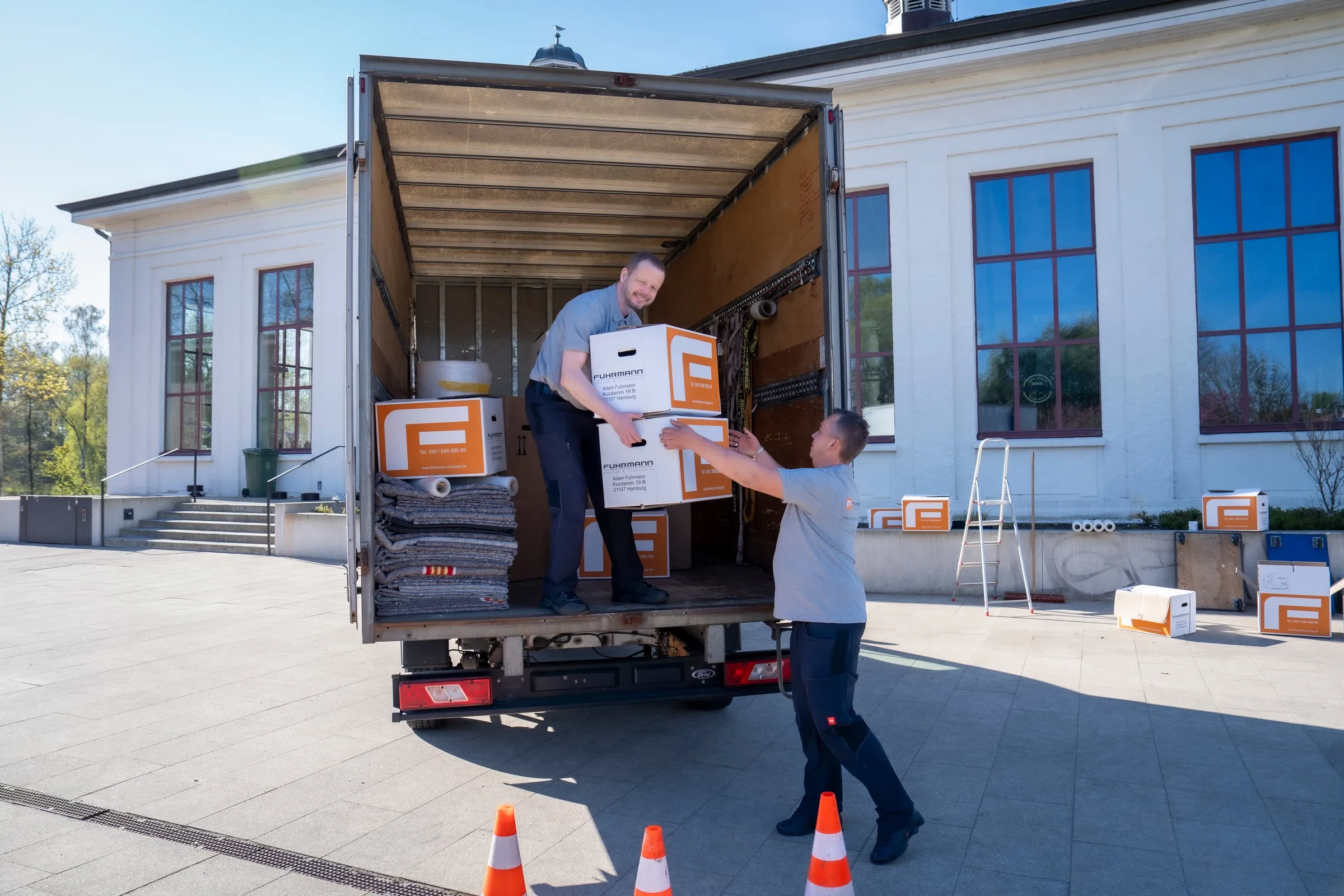 Fuhrmann-Mitarbeiter reicht Karton in den Umzugs-LKW – schneller Hamburger Express-Umzug