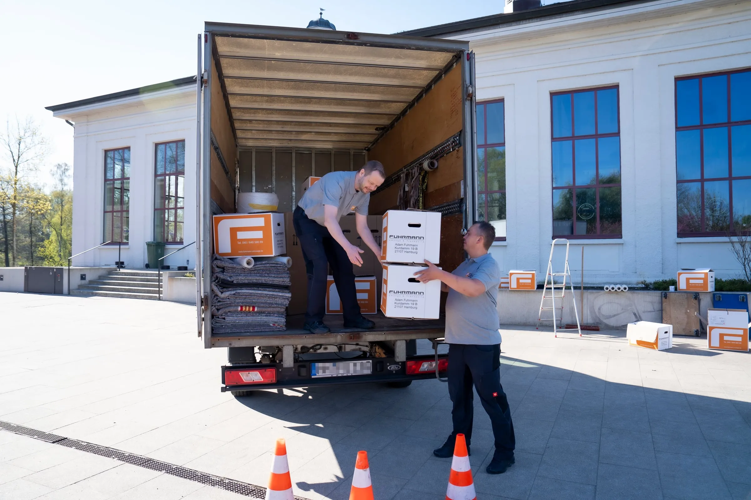 Fuhrmann-Umzugsteam belädt LKW mit gebrandeten Boxen vor Hamburger Altbau