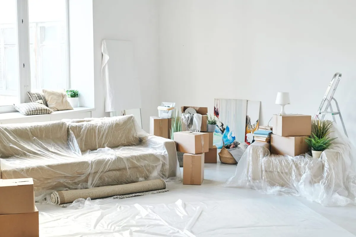 Wohnzimmer mit eingepackten Möbeln und Kartons während eines WG-Umzugs