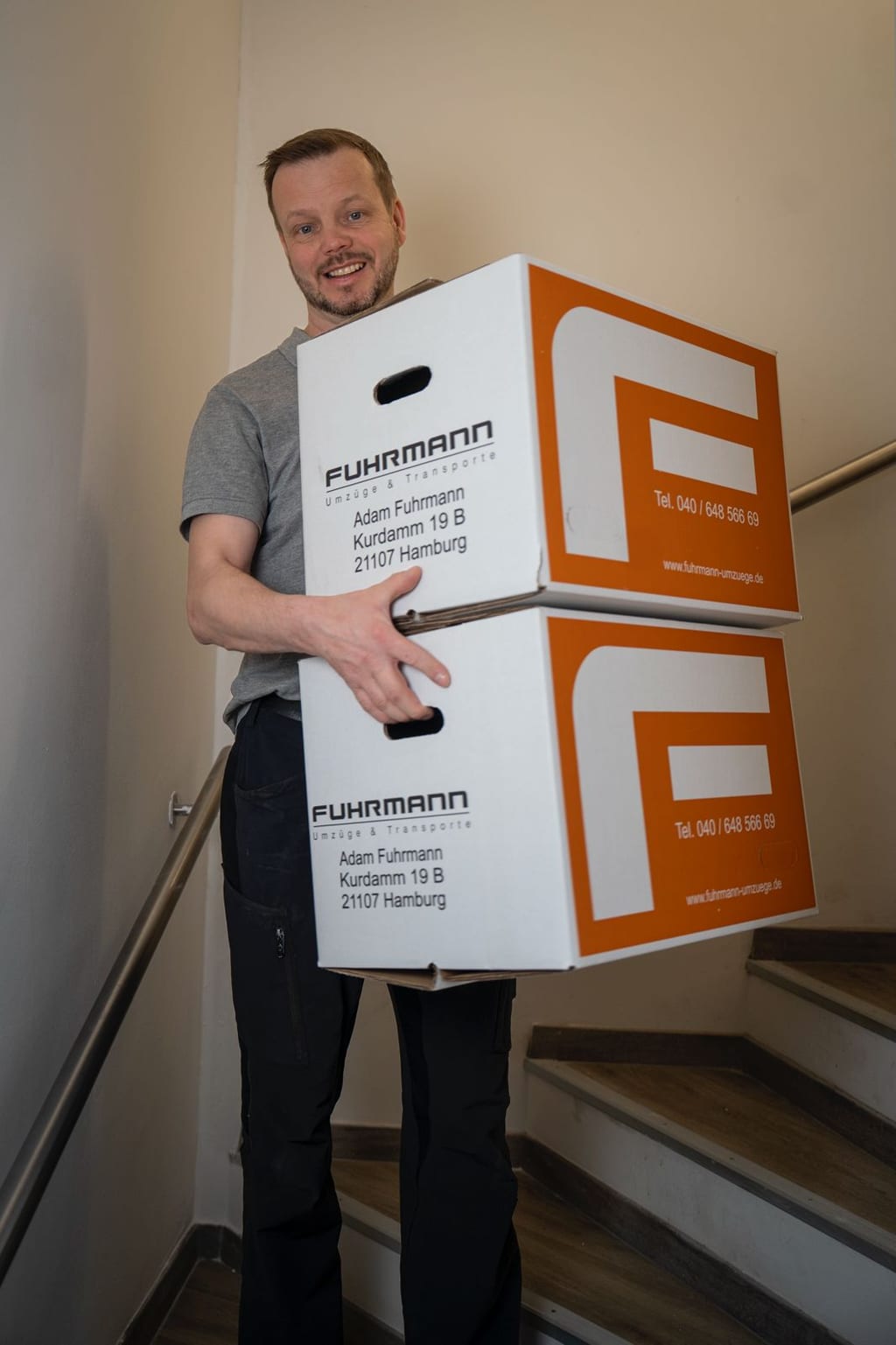 Adam Fuhrmann beim Tragen von Umzugskartons im Treppenhaus